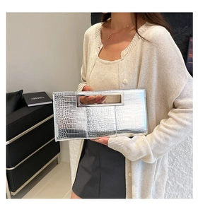 Close-up of shiny silver crocodile embossed leather clutch with hollow metal handle