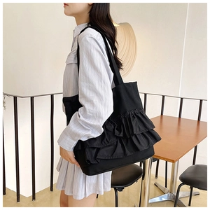 Detail of black canvas tote bag showing multiple layers of stylish ruffled pleats on model