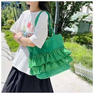 Detail of green pleated canvas tote bag showing the layered ruffle design and large capacity
