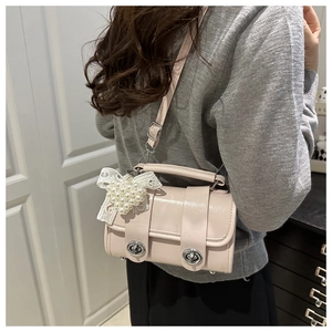 Détail d'un sac à main en cuir verni rose clair avec boucles métal et breloque cœur perle