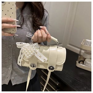 Détail du sac polochon crème avec boucles argentées et pendentif nœud en perles