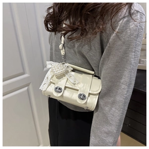 Détail du sac polochon blanc cassé en PU avec charme cœur perlé et nœud en dentelle