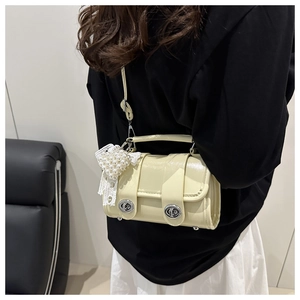 Détail du sac crème avec fermoirs rotatifs argentés et charm floral en dentelle
