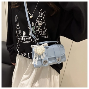 Détail du sac en cuir bleu clair avec fermoirs rotatifs argentés et pendentif cœur perlé