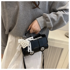 Détail du sac cylindrique noir brillant avec boucles argentées et breloque en perles
