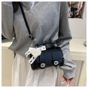 Détail du sac bandoulière cylindrique noir brillant avec fermoirs argentés et perles