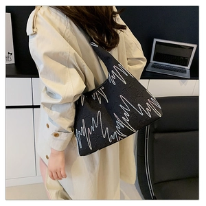Detail of a black tote bag with white zigzag pattern and textured grain fabric finish