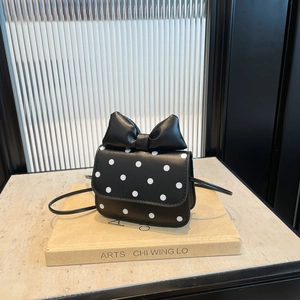 Polka dot mini crossbody bag with large bow detail on modern interior background