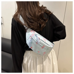 Détail du sac bandoulière fleuri avec tirettes tressées bleues et deux compartiments