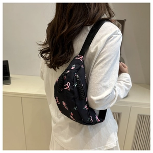 Détail du sac bandoulière en nylon noir avec motif fleurs roses et nœuds sur la sangle