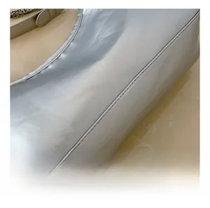 Detailed close-up of metallic silver bag stitching and durable chain strap with leather pad