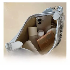 Macro view of silver underarm bag interior showing large capacity for makeup and phone