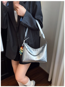 Detail of silver metallic crescent bag with chain strap and pearl charm pendant