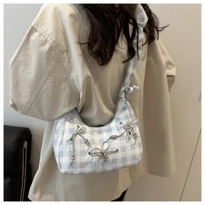 Detail of blue and white checkered shoulder bag featuring bow ornaments and ruffled strap