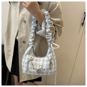 Detail of light blue plaid shoulder bag with gray bows and silver bead decorations