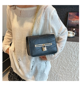 Detail of black patchwork shoulder bag with gold heart padlock and metal chain strap
