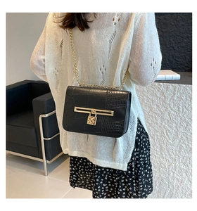 Detail of black crocodile texture bag with gold chain strap and heart-shaped lock