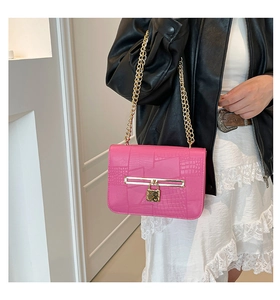 Detail of pink faux crocodile leather texture and gold heart padlock on chain bag