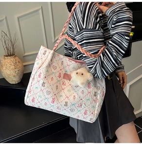 Detailed view of beige tote bag with floral bear embroidery and pink braided strap
