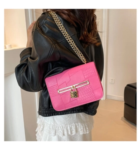 Detail of fuchsia crocodile pattern shoulder bag with gold chain and heart lock