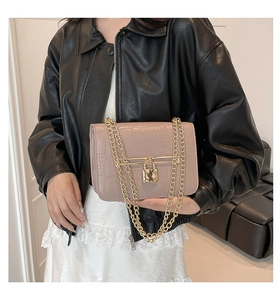 Detail of light pink crocodile pattern leather bag with gold chain and padlock decoration
