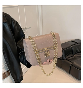 Detail of crocodile embossed crossbody bag with golden heart lock and chain strap