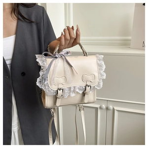 Close-up of cream faux leather backpack featuring lace edges and ribbon bow details