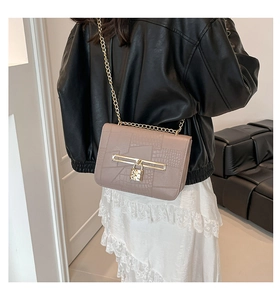 Detail of pink faux leather crossbody bag with crocodile texture and gold padlock