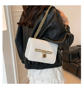 Close-up of white crocodile pattern shoulder bag with golden chain and metallic lock