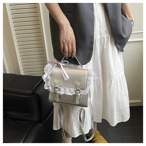 Detail of silver metallic bag featuring lace trim, purple plaid bow and cat ear stitching