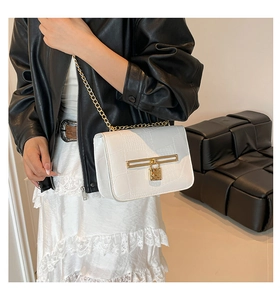 Chic white crossbody bag with crocodile texture and gold chain worn by a fashion model