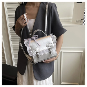 Silver metallic crossbody bag with lace trim and bow details worn by a model