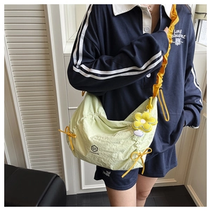 Détail du sac croissant en nylon vert pistache avec cordons jaunes et breloque tournesol