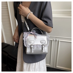 Silver metallic crossbody bag with white lace trim and bow buckle details on model