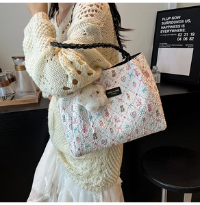 Detail of printed tote bag with woven handles and cute bear charm in a cafe setting
