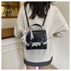 Detail of black faux leather backpack with white lace trim and bow embossing