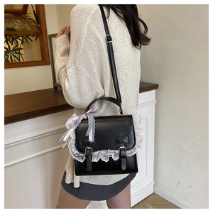 Detail of a sweet Lolita style black handbag featuring lace edges and a pink ribbon bow