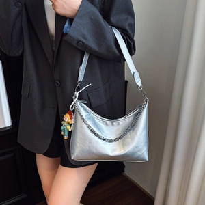 Metallic silver hobo shoulder bag with square link chain and cartoon doll on a model