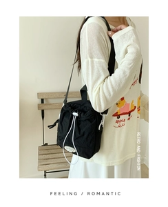 Detailed view of black nylon drawstring crossbody bag with fashion metal plate logo