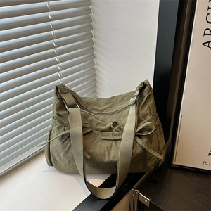 Detail of army green pleated messenger bag with decorative side bows and wide shoulder strap