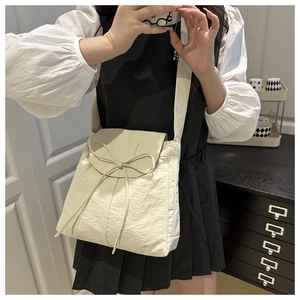 Dettaglio della borsa a tracolla crema con fiocco decorativo e texture in nylon