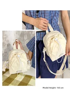 Detail of off-white drawstring crossbody bag on 165cm model with adjustable strap