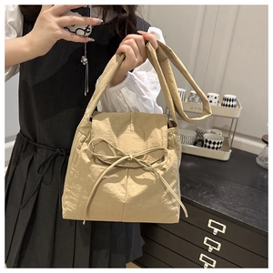 Dettaglio borsa a tracolla in tessuto beige con coulisse a fiocco e cinturino largo