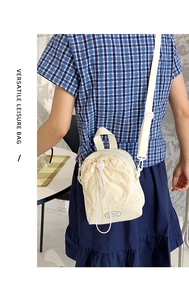 Versatile off-white drawstring leisure bag with adjustable strap worn by a model