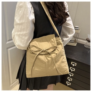 Dettaglio della borsa tote in nylon beige con fiocco e trama plissettata casual
