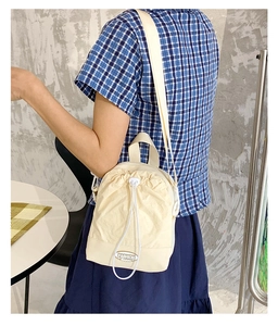 Detail of cream drawstring crossbody bag in ripstop fabric with adjustable strap