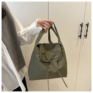 Dettaglio della borsa in tessuto verde oliva con fiocco decorativo e trama increspata