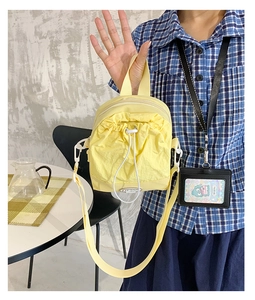 Macro detail of yellow nylon crossbody bag featuring drawstring pocket and top handle