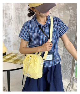 Adjustable light yellow nylon crossbody bag with drawstring pocket and round logo patch
