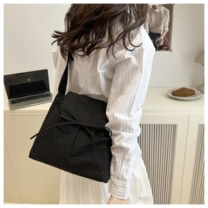 Dettaglio della borsa tote in nylon nero minimalista con fiocco decorativo in corda